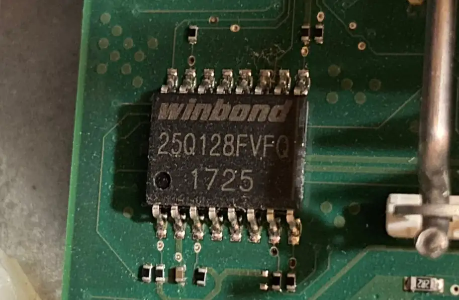 A small SOIC-16 flash memory chip soldered to the computer's system board.